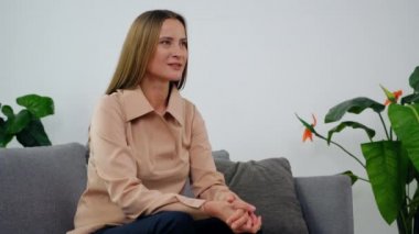 Kanepede oturup psikologla konuştuktan sonra zihinsel sorunları olan gülümseyen yetişkin bir kadın. Doktor psikoterapist, klinikteki psikoterapi seansında hastayı dinle.