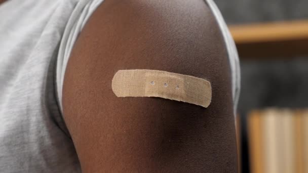 Закрыть вакцинированного афроамериканца с медицинской штукатуркой на плече — стоковое видео