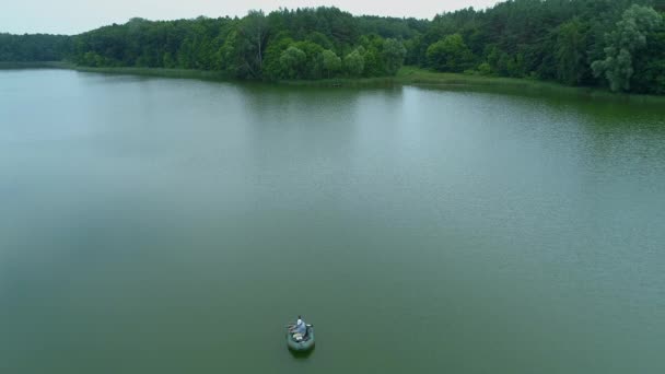 Pescador da vista aérea está pescando sentado em um barco inflável no meio do lago — Vídeo de Stock