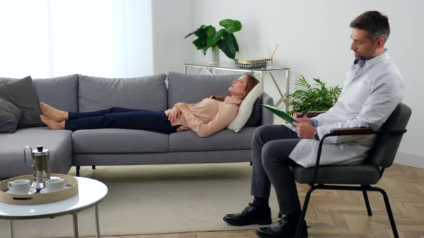 Mujer adulta con problemas de salud mental acostada en el sofá hablando con el terapeuta — Vídeos de Stock