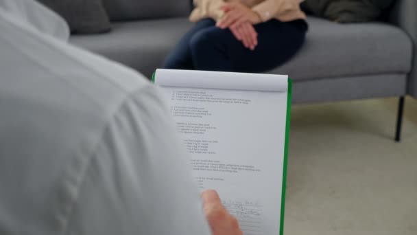 Mann aus nächster Nähe Psychotherapeut hört Patient zu und macht Notizen auf Klemmbrett — Stockvideo