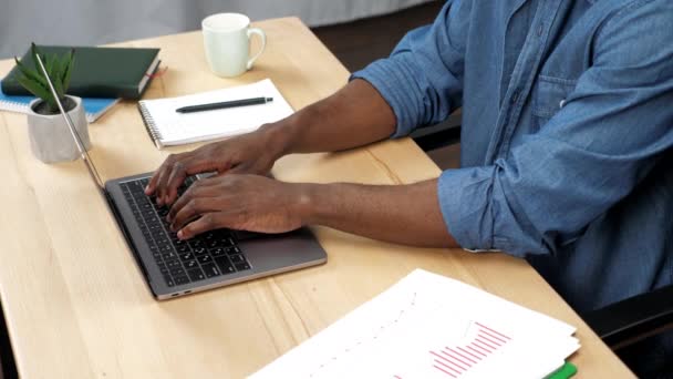 Афроамериканец работает на ноутбуке, печатая на клавиатуре в офисе — стоковое видео