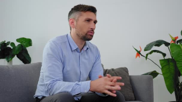 Hombre adulto con problemas de salud mental sentado en el sofá hablando con el psicólogo — Vídeo de stock