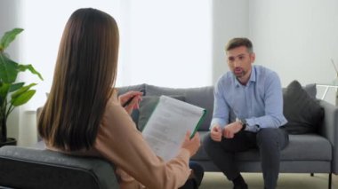 Psikolojik sorunları olan ve terapistle konuşan odaksız gülümseyen bir adam.