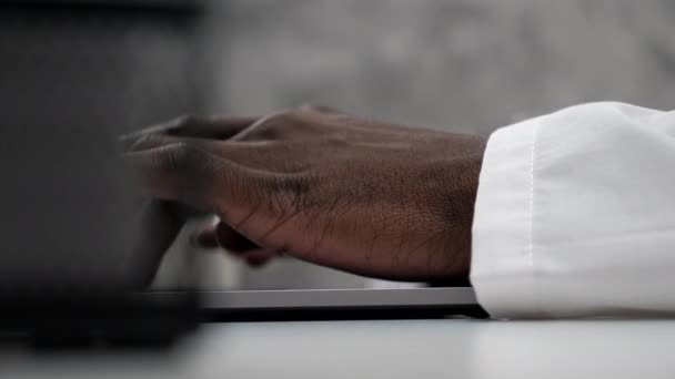 Mani in primo piano afroamericano uomo medico digitando sul computer portatile tastiera in clinica — Video Stock