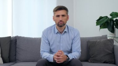 Klinikteki koltukta oturan üzgün adamın portresi. Kameraya bakıyor.