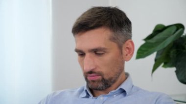 Mavi gömlekli iş adamını kapat. Tablet bant ekranı kullanarak kanepeye otur.