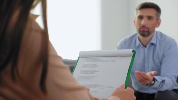 Unfocused man with mental health problems sitting on couch talking to therapist — Stock Video