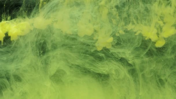 Gelbe Tinte Acrylfarbe tropft in Wasser und mischt sich, wirbelt sanft unter Wasser — Stockvideo