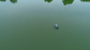 Hava manzaralı balıkçı gölün ortasında şişme bir teknede balık tutuyor.