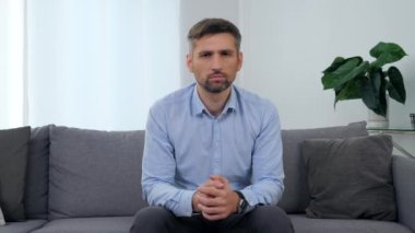 Klinikteki koltukta oturan üzgün adamın portresi. Kameraya bakıyor.