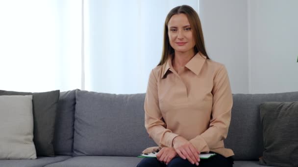 Positive woman psychologist in beige blouse sitting on couch in clinic office — Stock Video