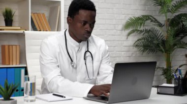 Klinikteki klavye bilgisayarında yazı yazan Afrikalı bir doktor.