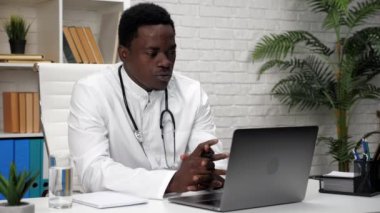 Afrikalı Amerikalı doktor hasta ile konuşuyor. Web kamerası laptopu.