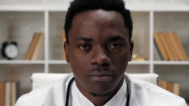Крупным планом афроамериканец смотрит в камеру в больничном кабинете — стоковое видео