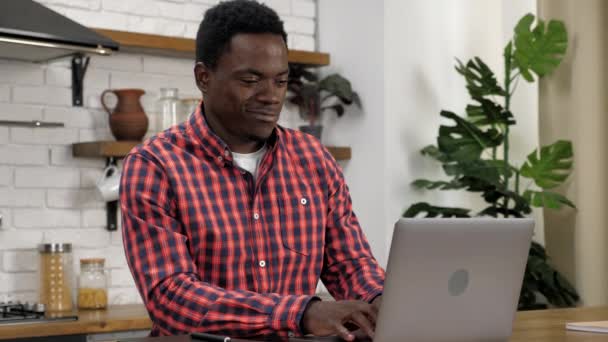 Sorridente uomo afroamericano studente studio fa i compiti a casa utilizzando il computer portatile — Video Stock