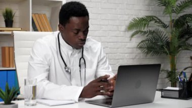 Afrikalı Amerikalı doktor hasta ile konuşuyor. Web kamerası laptopu.