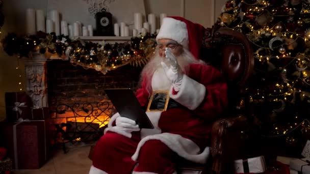 현대의 미소짓는 산타클로스가 온라인 웹캠 비디오 태블릿 전화로 아이들에게 인사를 건다 — 비디오