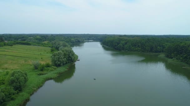 Вид с воздуха красивый лес природы и озеро, в котором рыбак рыбачит — стоковое видео