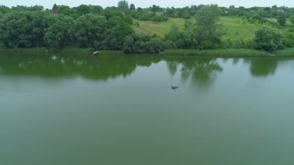 Pescador da vista aérea está pescando sentado em um barco inflável no lago — Vídeo de Stock