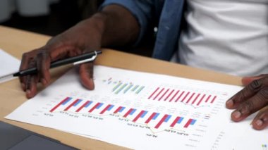 Afrika kökenli Amerikalı işadamı iş raporuna grafik şirketi göstergeleriyle bakıyor