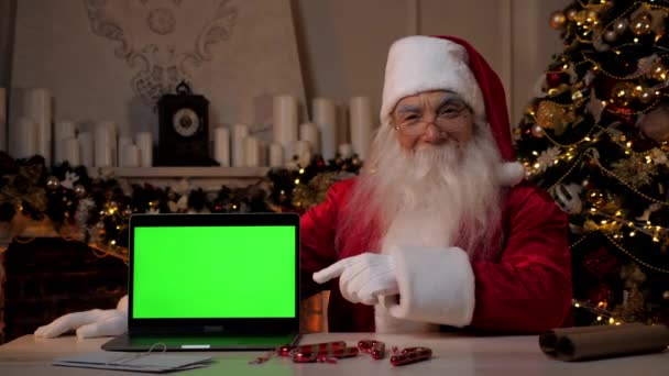 Usmívající se Santa Claus ukazuje prst na zelené obrazovce notebooku, vánoční nákupy — Stock video