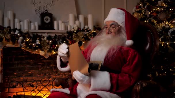 Santa Claus membaca surat dengan daftar hadiah dari anak-anak untuk liburan Natal — Stok Video