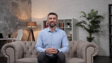 Portre gülümseyen borsa simsarı koltukta oturan kameraya bakıyor.