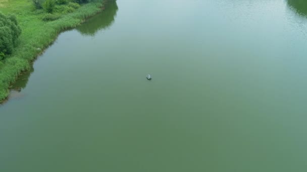 Pescador da vista aérea está pescando sentado em um barco inflável no lago — Vídeo de Stock