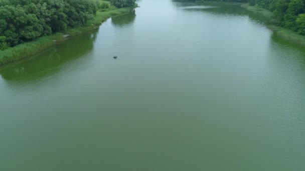 Pescador da vista aérea está pescando sentado em um barco inflável no lago — Vídeo de Stock