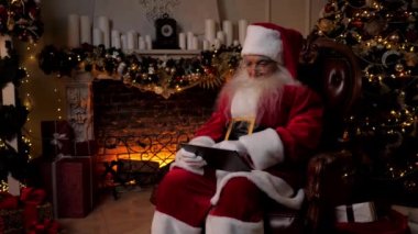 Modern Noel Baba tablet üzerinde çalışır. Çocuklar için internetten Noel hediyesi alır.