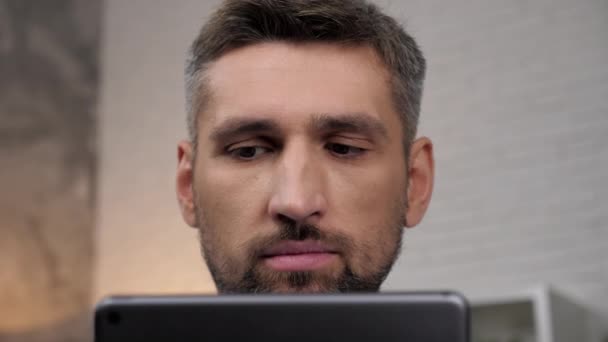 Close-up gezicht hoofd zakenman maakt gebruik van tablet zitten op de bank thuis kantoor — Stockvideo