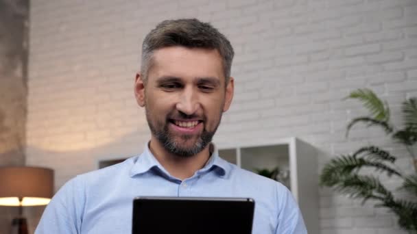 密切关注微笑的男性交易员看着平板电脑分析股票交易所的报价 — 图库视频影像