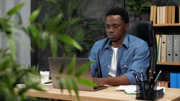Afroamerykański biznesmen pracuje na laptopie czatując z pracownikami firmy — Wideo stockowe