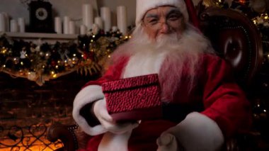 Gülümseyen Noel Baba, Noel tatili için kırmızı bir kutuda hediye verir.