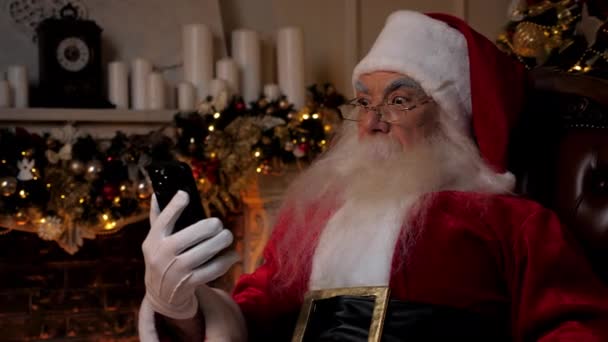 Chocado Papai Noel olha para o smartphone, vira a cabeça de surpresa, olha câmera — Vídeo de Stock