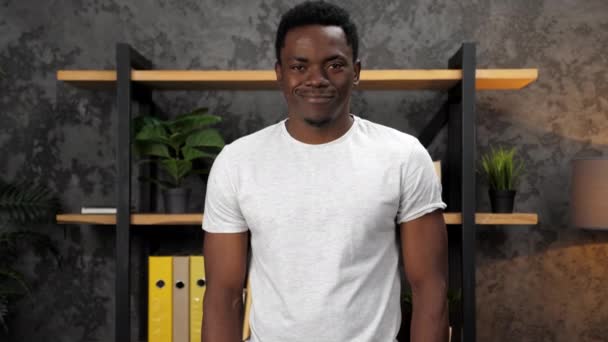 Lächelnder Afroamerikaner blickt Kamera auf Hintergrundbüro-Inventar — Stockvideo