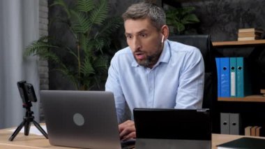 Şok olmuş işadamı dizüstü bilgisayara, tablete ve akıllı telefon ekranına bakıyor