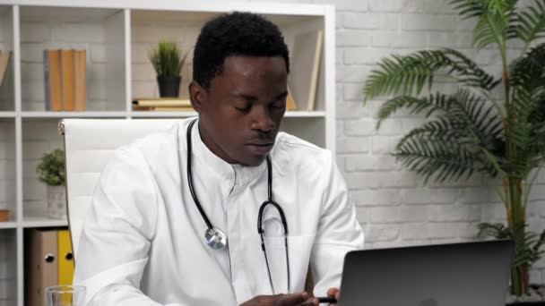 Афроамериканец онлайн врач разговаривает с пациентом видео вызова веб-камера ноутбука — стоковое видео