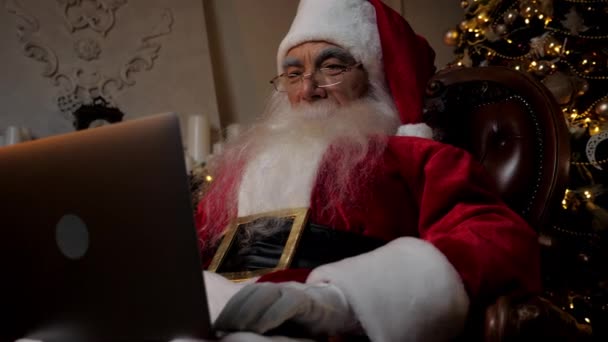 Закрыть современный Санта-Клаус использует ноутбуки заполняет праздничные карты для детей — стоковое видео