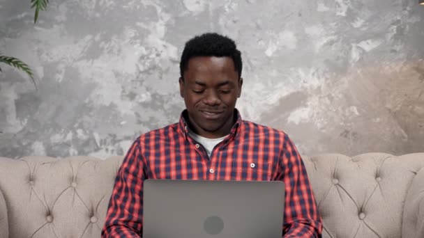 Sonriente hombre de negocios afroamericano trabaja para computadora portátil charlando con los empleados — Vídeo de stock