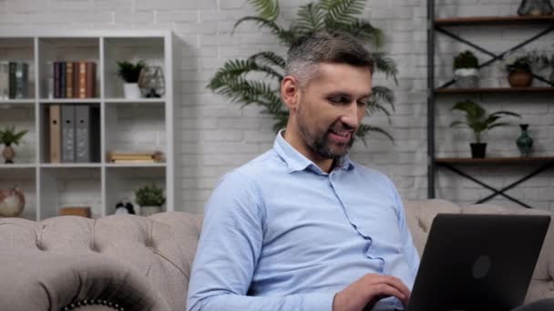 Homme souriant courtier boursier travaille pour ordinateur portable chat en ligne avec l'investisseur — Video