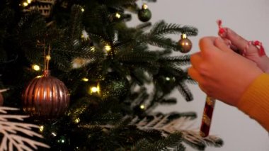 Ellerini kapat, kadın Noel ağacını yeni yıl süslemeleriyle süslüyor.