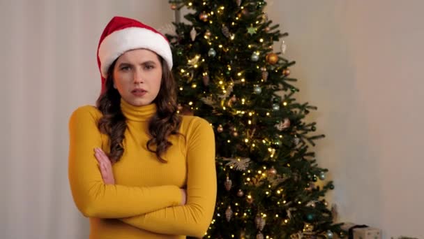 Portrét naštvaný mladá žena v klobouku Santa Claus kříží ruce vypadá fotoaparát doma — Stock video