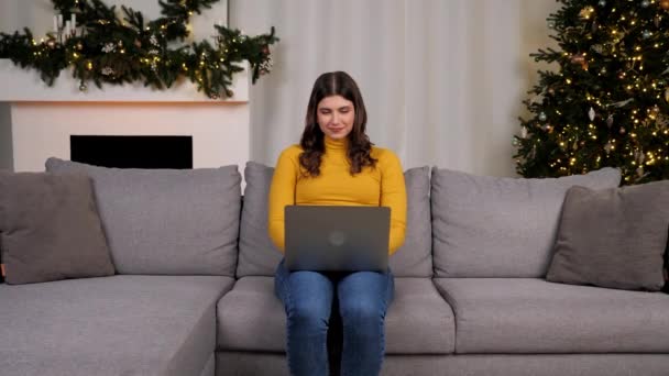 Mulher usa laptop online conversando com amigos no fundo Árvore de Natal — Vídeo de Stock