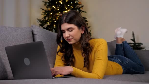 Vrouw maakt gebruik van laptop online chatten met vrienden op de achtergrond kerstboom — Stockvideo