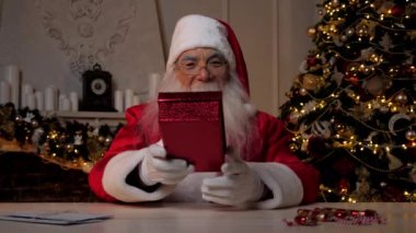 Gülümseyen Noel Baba bayram bayramlarında kırmızı bir kutuda hediye verir.
