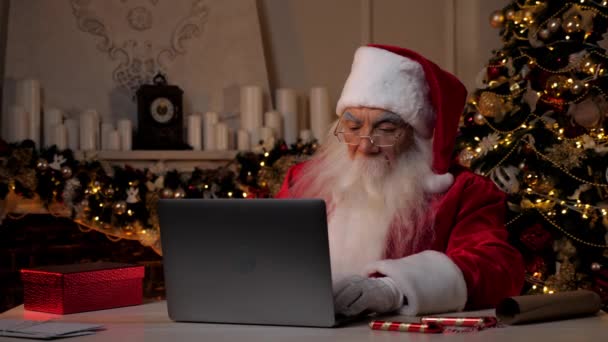 Le Père Noël moderne utilise un ordinateur portable achète des cadeaux de Noël pour les enfants sur Internet — Video