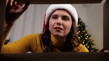 Kutuda Noel Baba şapkalı gülümseyen kadın Noel kutusunu açıyor, üzgün.