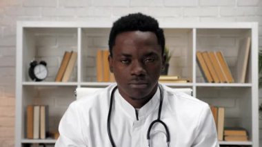Afro-Amerikalı doktor doktor hastanedeki kameraya bakıyor.